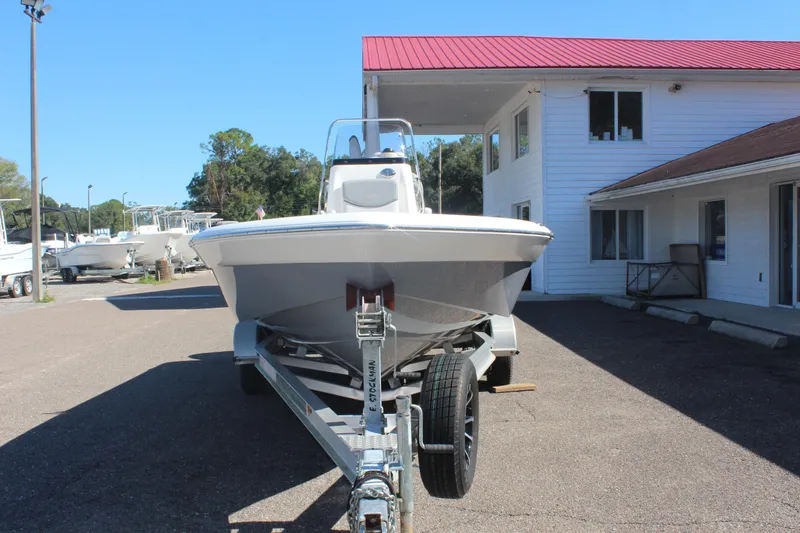 Slide: The Image of 2022 NauticStar 227 Bay boat on trailer, parked outside a building with red roof. - 10