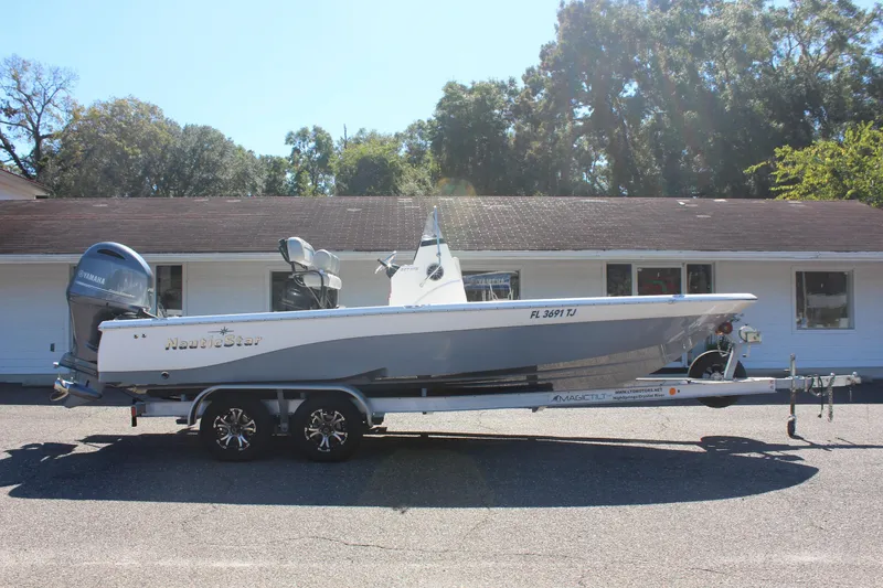 Slide: The Image of 2022 NauticStar 227 Bay boat on trailer, parked in front of a building. - 12