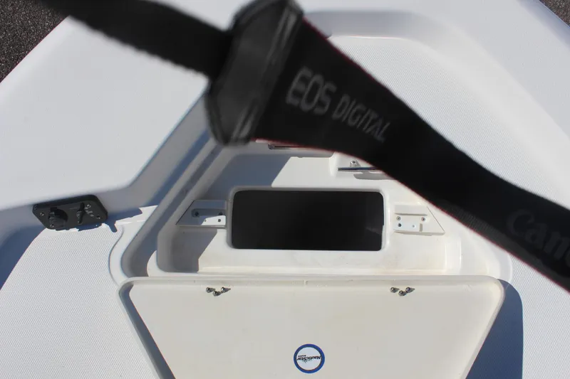 Slide: The Image of 2022 NauticStar 227 Bay boat interior with storage compartment and EOS Digital camera strap. - 24