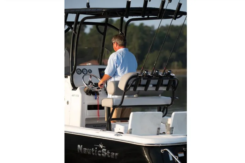 Slide: The Image of Manufacturer Provided Image: 2022 NauticStar 227 Bay boat with man at the helm, fishing rods in holders. - 3