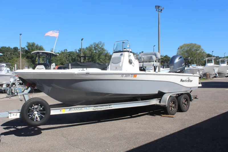 Slide: The Image of 2022 NauticStar 227 Bay boat on trailer, parked outdoors under clear blue sky. - 9