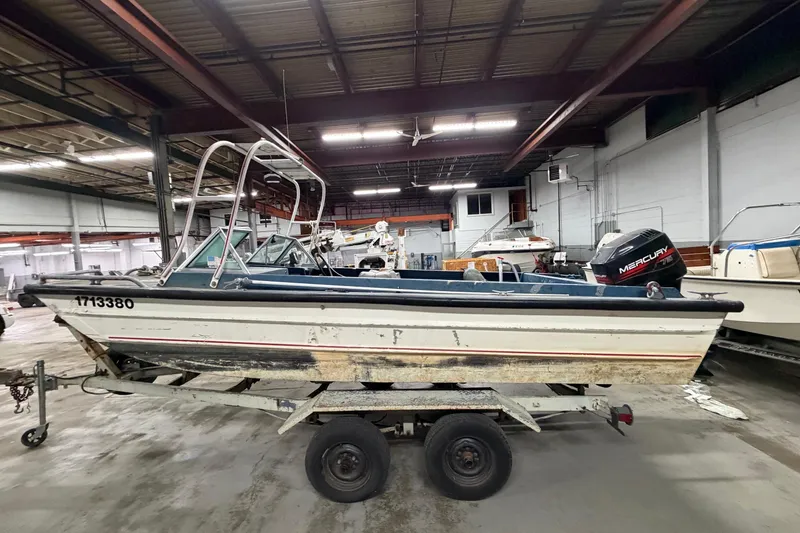 Slide: The Image of 1976 Monark 17 Utility Outboard boat on trailer in indoor storage facility. - 2