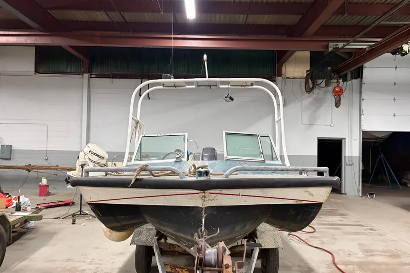 Slide: The Image of 1976 Monark 17 Utility Outboard boat in a garage, front view with Evinrude motor. - 3
