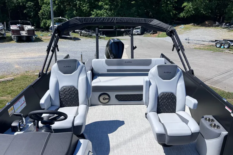 Slide: The Image of 2026 Alera M23L boat interior with modern seating and steering wheel, parked outdoors. - 8