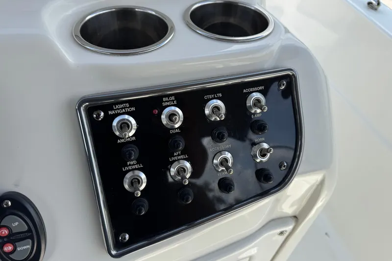 Slide: The Image of Control panel of a 2020 NauticStar 231 Hybrid boat with switches and cup holders. - 20