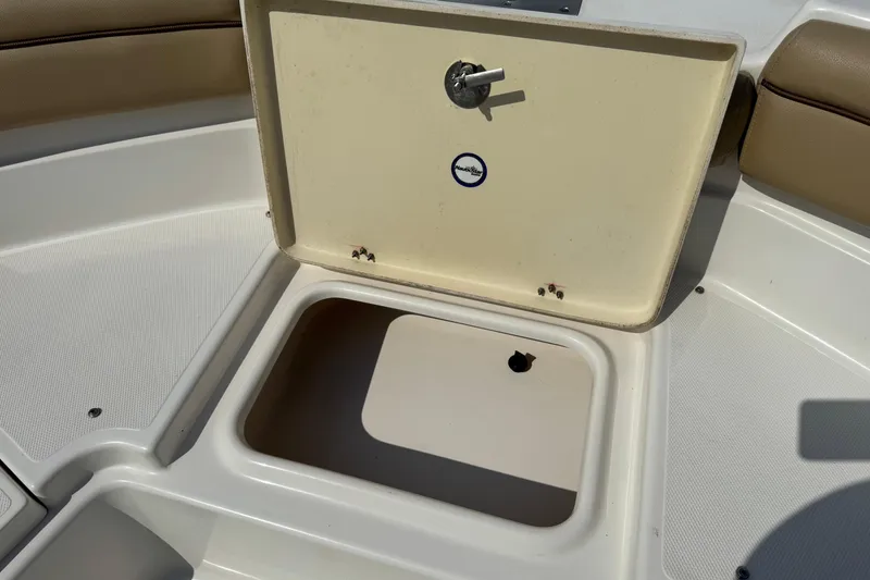 Slide: The Image of Open storage compartment on a 2020 NauticStar 231 Hybrid boat, featuring beige interior. - 29