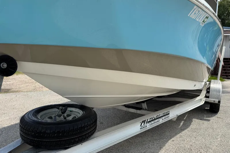 Slide: The Image of 2020 NauticStar 231 Hybrid boat on trailer, blue hull, parked outdoors. - 3
