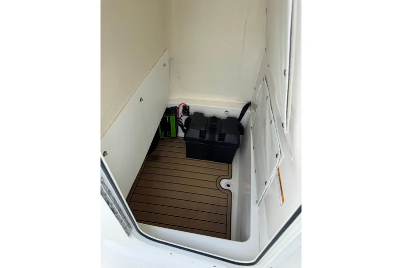 Slide: The Image of 2020 NauticStar 231 Hybrid boat storage compartment with battery and wooden flooring. - 32