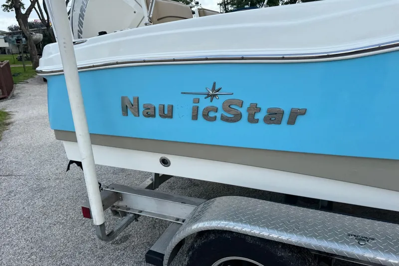Slide: The Image of 2020 NauticStar 231 Hybrid boat on trailer, featuring blue and white exterior. - 9