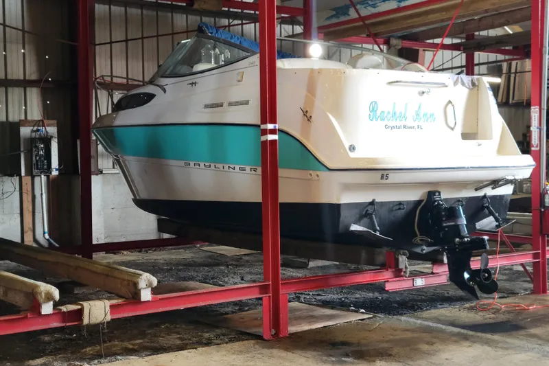 The Image of 2003 Bayliner 245 boat in storage, Crystal River, FL, on red metal supports. - 0