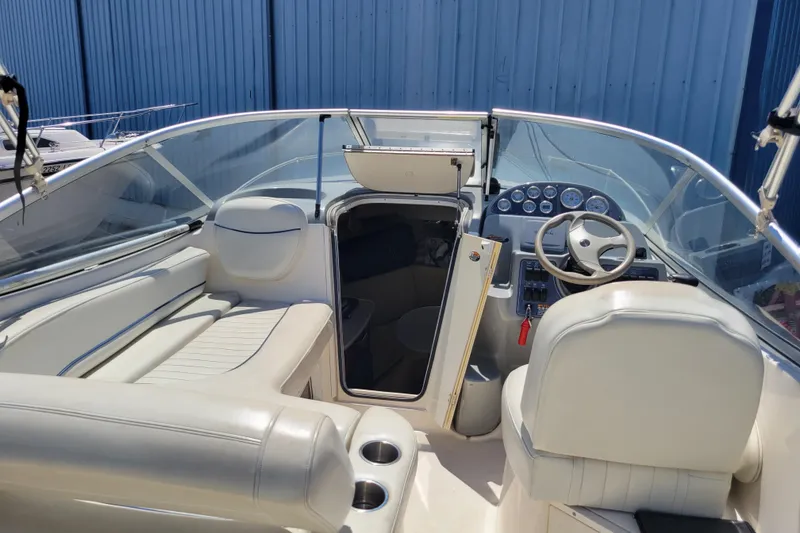 Slide: The Image of 2003 Bayliner 245 boat interior with steering wheel, seating, and cabin entrance. - 4