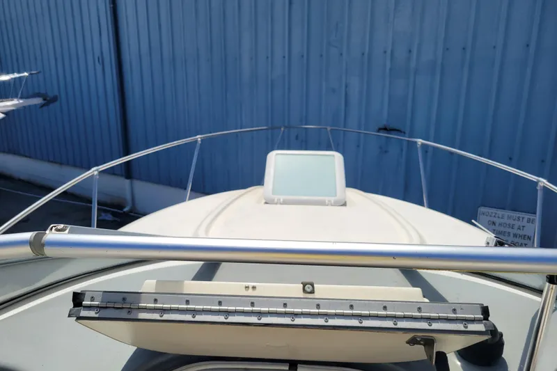 Slide: The Image of 2003 Bayliner 245 boat deck with railing, docked near a blue metal wall. - 6