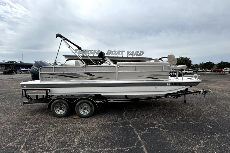 The Image of 2014 Hurricane FunDeck 226F boat on trailer in parking lot, overcast sky. - 0