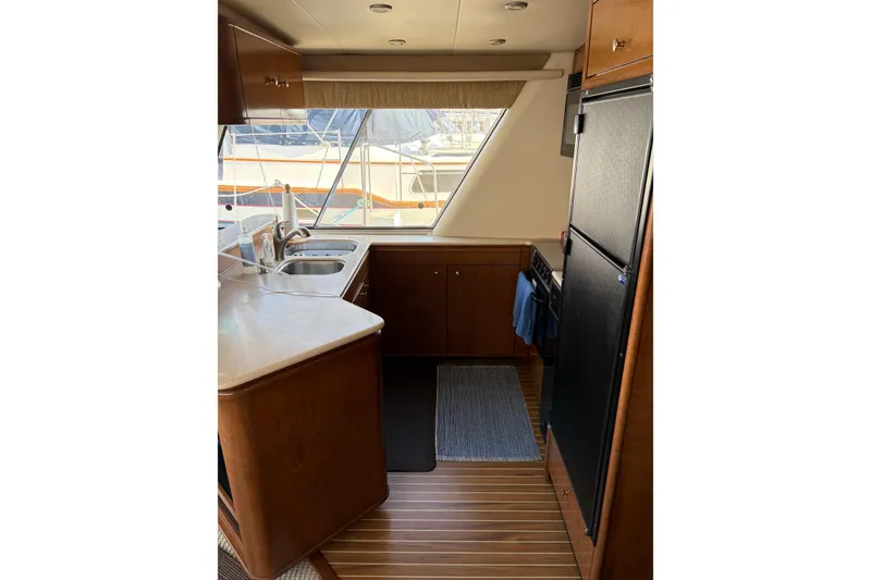Slide: The Image of 2005 Meridian 490 Pilothouse kitchen with wood cabinetry, dual sinks, and large refrigerator. - 6
