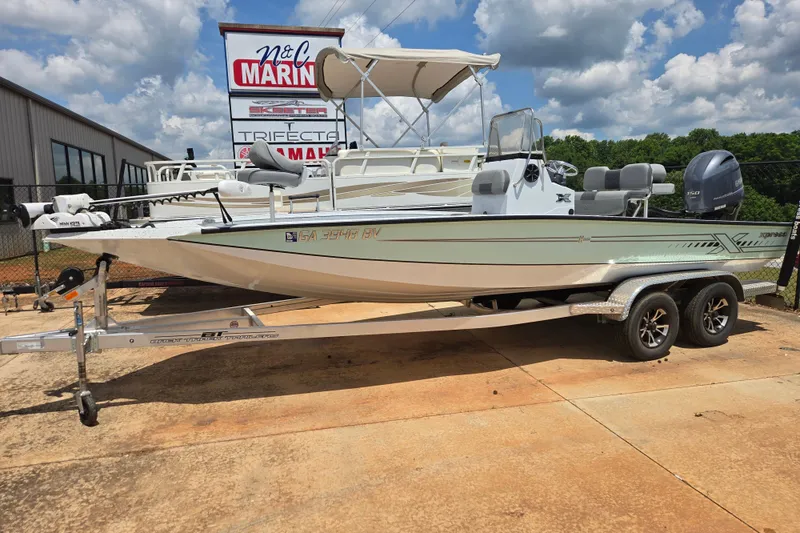 The Image of 2023 Xpress H22B Bay boat on trailer at dealership, sunny day. - 1