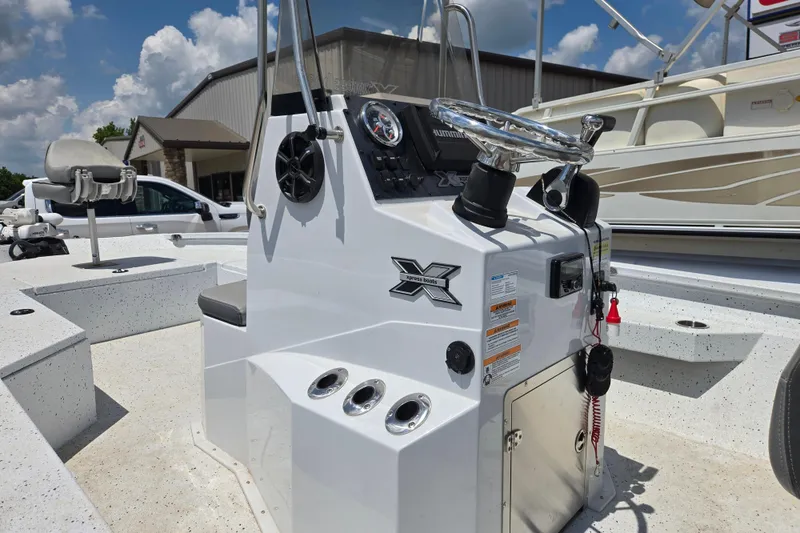 Slide: The Image of 2023 Xpress H22B Bay boat console with steering wheel and controls under a sunny sky. - 13