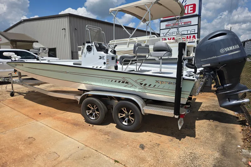 Slide: The Image of 2023 Xpress H22B Bay boat with Yamaha motor on trailer, parked outdoors. - 2