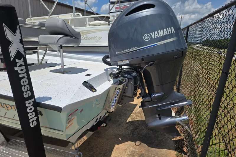 Slide: The Image of 2023 Xpress H22B Bay boat with Yamaha outboard motor, parked near a fence. - 3