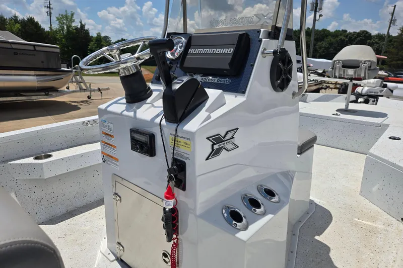 Slide: The Image of 2023 Xpress H22B Bay boat console with steering wheel and controls, under a sunny sky. - 6