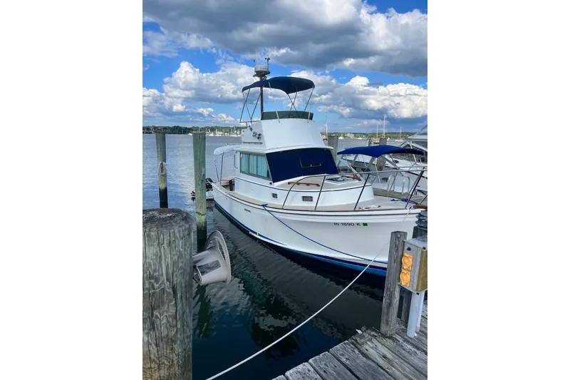 Slide: The Image of 1987 Cape Dory 28 Flybridge boat docked at a marina under a partly cloudy sky. - 1