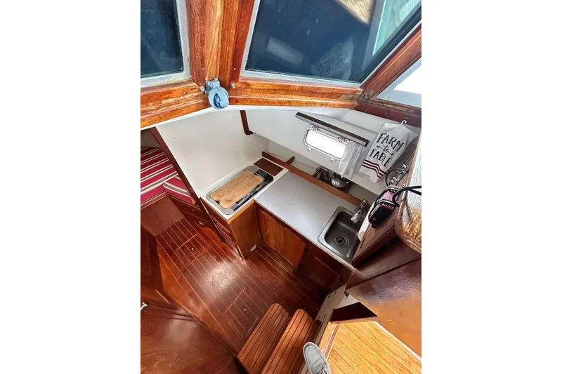 Slide: The Image of 1987 Cape Dory 28 Flybridge interior galley with wooden cabinetry and compact kitchen amenities. - 4
