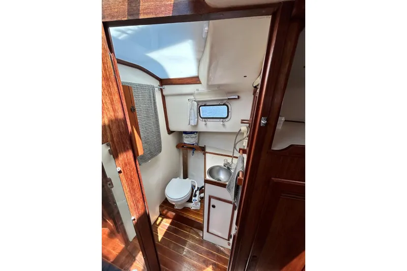 Slide: The Image of 1987 Cape Dory 28 Flybridge boat interior with wooden finish and compact bathroom. - 7