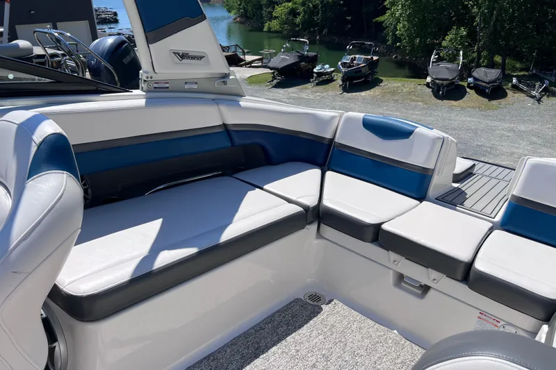 Slide: The Image of 2016 Chaparral Vortex 243 VRX boat interior with blue and white seating near a lake. - 14