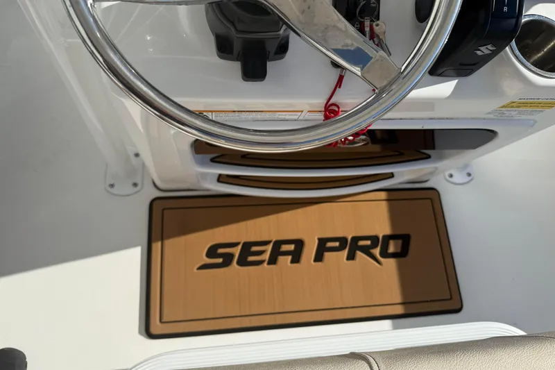 Slide: The Image of 2024 Sea Pro 210 Bay boat helm with steering wheel and branded mat. - 15