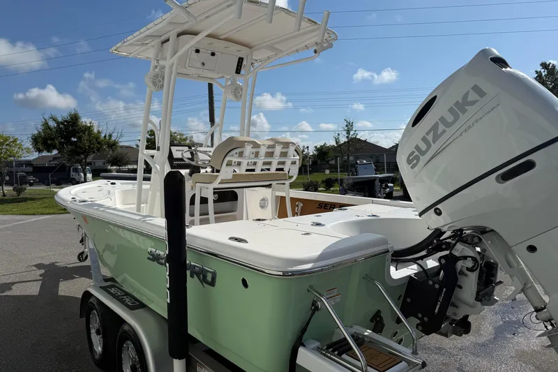 Slide: The Image of 2024 Sea Pro 210 Bay boat with Suzuki engine, parked on a trailer under a clear sky. - 4