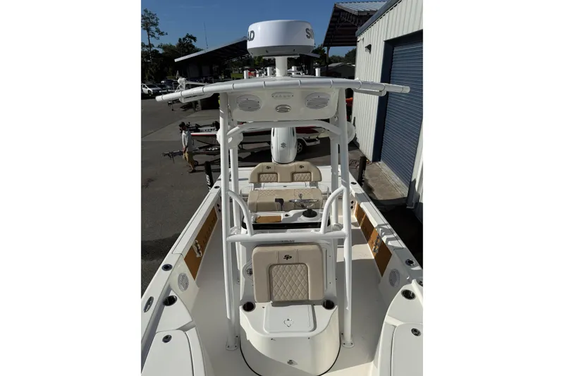 Slide: The Image of 2024 Sea Pro 210 Bay boat with T-top and seating, docked near a warehouse. - 9