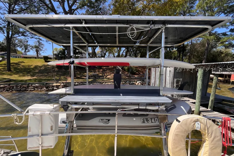 Slide: The Image of Broadblue 415 catamaran with solar panels and paddleboards, docked by a scenic lakeside. - 11
