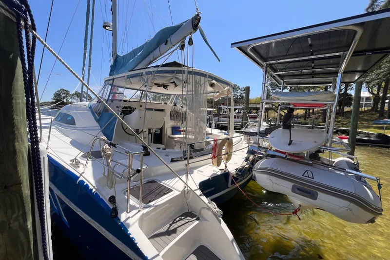 Slide: The Image of 2008 Broadblue 415 catamaran docked with dinghy, featuring blue and white design. - 2