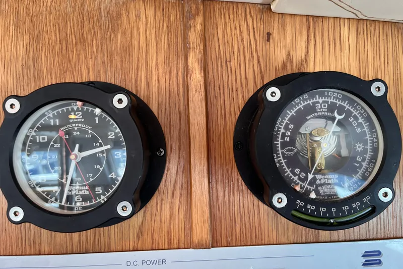 Slide: The Image of Analog gauges on a 2008 Broadblue 415 yacht dashboard, displaying time and barometric pressure. - 23