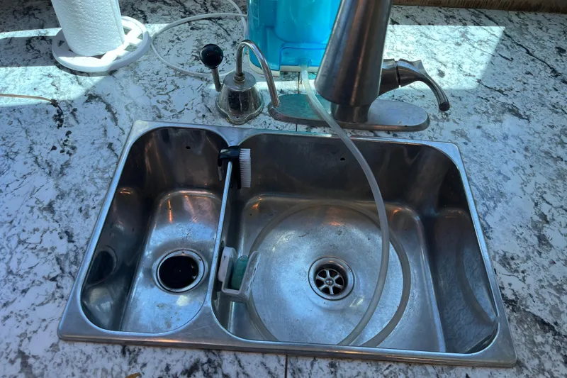 Slide: The Image of Stainless steel kitchen sink with faucet and cleaning brush on marble countertop. - 35