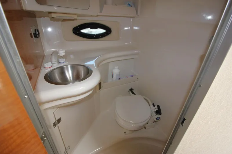 Slide: The Image of Compact bathroom in a 2002 Regal Commodore 2860 boat, featuring sink and toilet. - 26