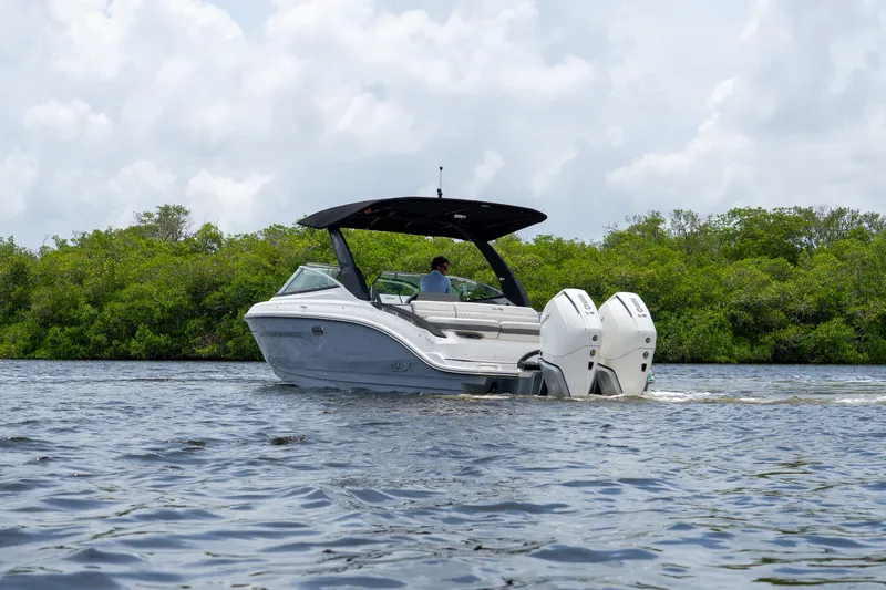 Slide: The Image of A 2027 Sea Ray SLX 280 Outboard cruising on calm waters with a green shoreline. - 31