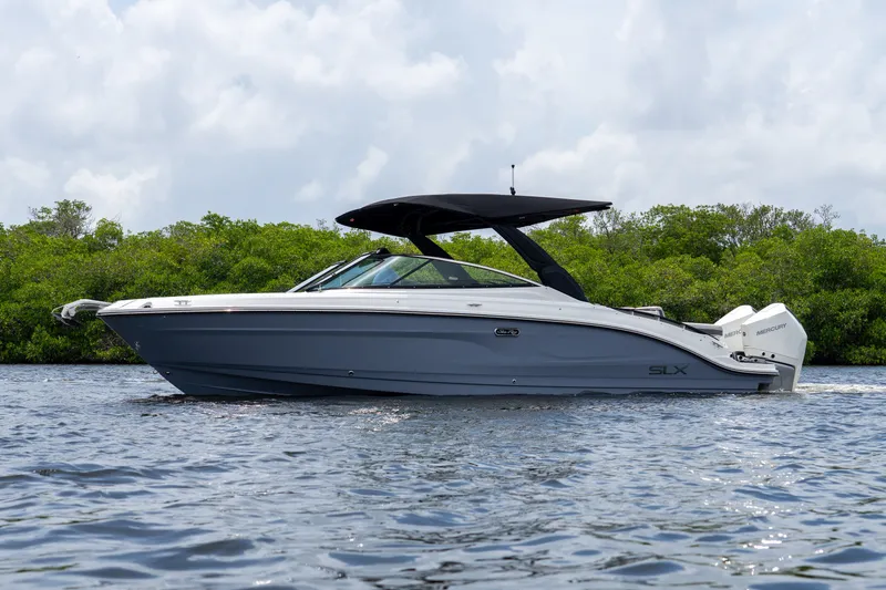 Slide: The Image of A sleek 2027 Sea Ray SLX 280 Outboard boat on calm water with a green backdrop. - 29