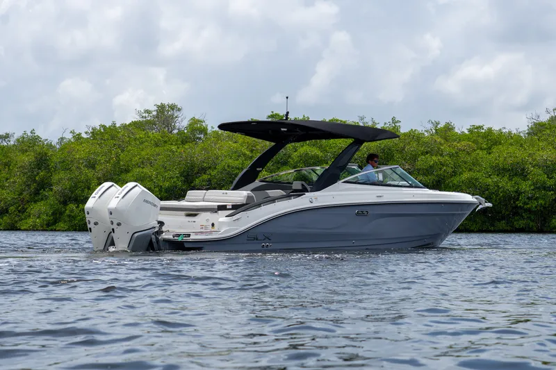 Slide: The Image of A 2027 Sea Ray SLX 280 Outboard cruising on calm waters, surrounded by lush greenery. - 24