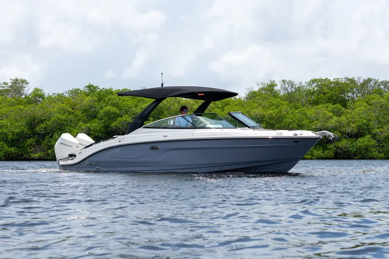 Slide: The Image of A 2027 Sea Ray SLX 280 Outboard cruising on calm water, surrounded by green vegetation. - 0