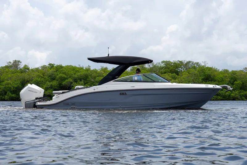 Slide: The Image of A sleek 2027 Sea Ray SLX 280 Outboard boat on calm water with a green backdrop. - 34