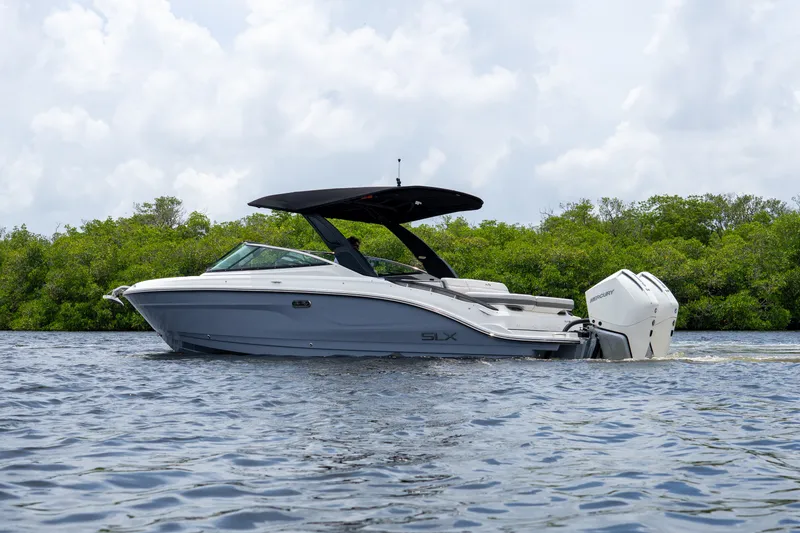 Slide: The Image of A sleek 2027 Sea Ray SLX 280 Outboard boat on calm water, surrounded by green vegetation. - 1