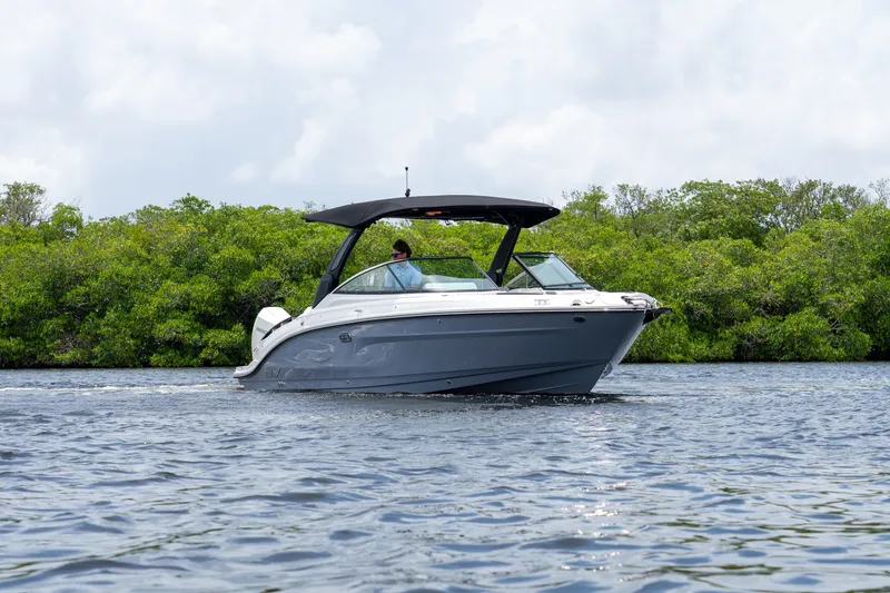 Slide: The Image of A 2027 Sea Ray SLX 280 Outboard cruising on calm waters, surrounded by lush greenery. - 27