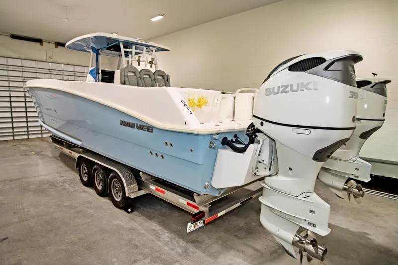 Slide: The Image of 2023 Twin Vee 340 GFX CC boat with Suzuki engines on a trailer in a garage. - 6