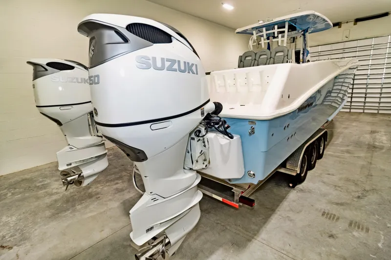 Slide: The Image of 2023 Twin Vee 340 GFX CC boat with dual Suzuki outboard motors in a garage. - 8