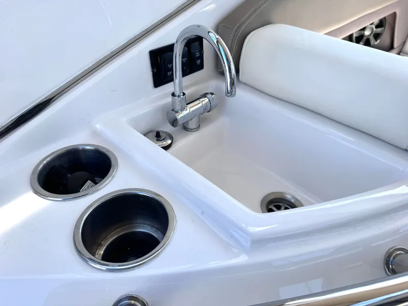 Slide: The Image of Regal 28 Express 2018 boat kitchenette with sink and cup holders. - 21