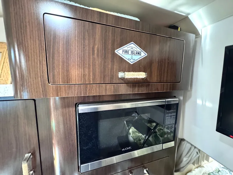 Slide: The Image of Interior of 2018 Regal 28 Express with microwave and cabinet. - 32