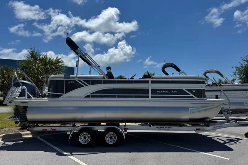 Slide: The Image of 2026 Bennington 22 SSR pontoon boat on trailer under clear blue sky. - 2