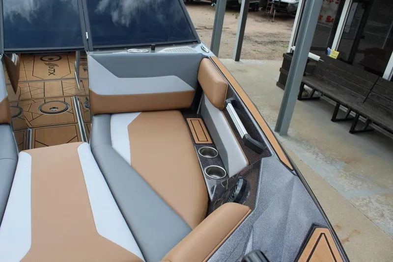 Slide: The Image of 2024 ATX Surf Boats 22 Type-S interior with tan and gray seating, cup holders, and sleek design. - 2