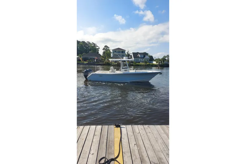 Slide: The Image of 2019 Sea Hunt Gamefish 27 boat docked on calm water under a clear sky. - 12