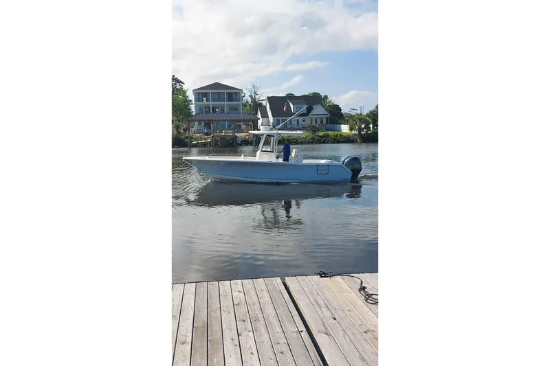 Slide: The Image of 2019 Sea Hunt Gamefish 27 boat on calm water near dock and houses. - 13